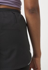Shorts negri de sport cu un design ajustat, realizate dintr-un material ușor. Au un mic buzunar cu fermoar în spate.