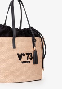 Vævet strå tote taske med sort stof top, læderhåndtag og kvast detaljer. Har V°73 branding med sort broderi.