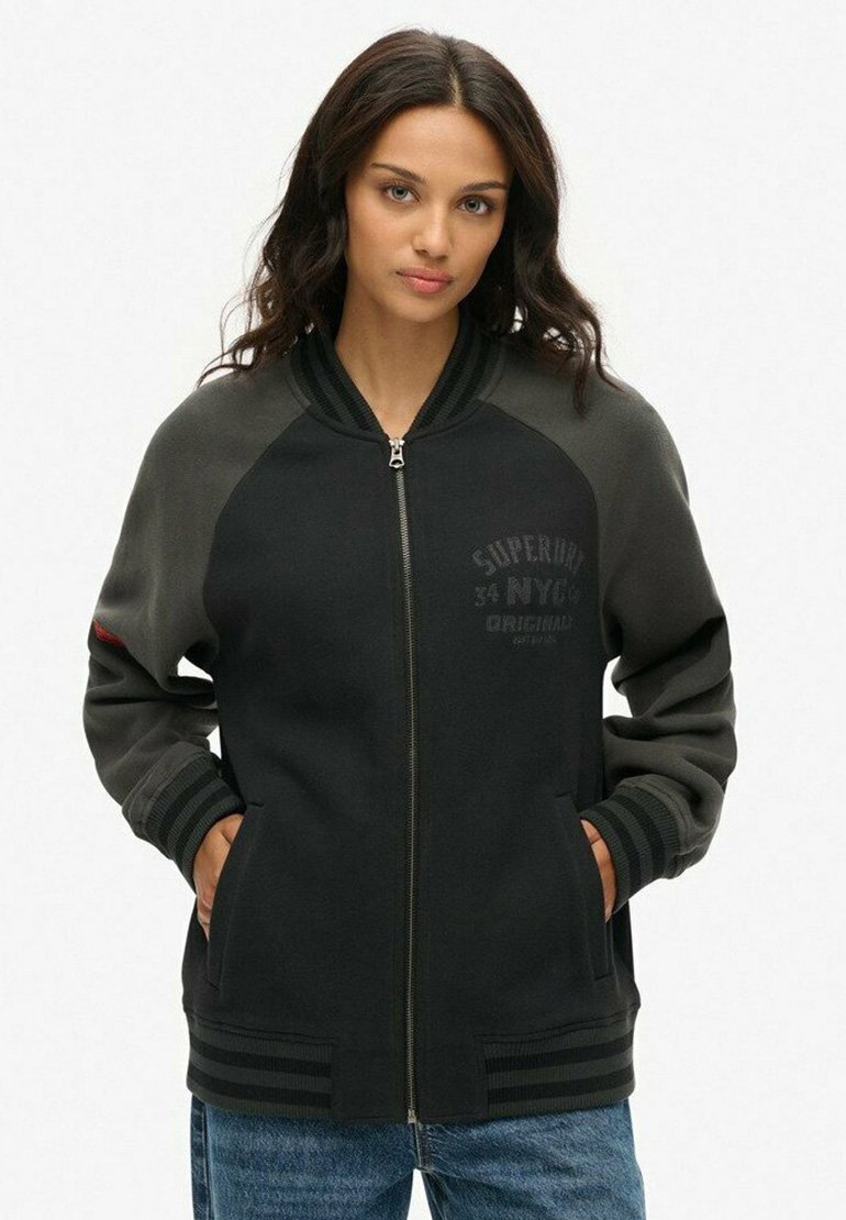 Zwarte en grijze zip-up jas met een geribde kraag en manchet, voorzien van zijzakken en subtiele logo-details op de voorkant.