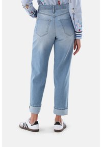 Hellblaue Denim-Jeans mit hoher Taille, geraden Beinen, umgeschlagenen Säumen und zwei Gesäßtaschen, kombiniert mit weißen Sneakers.