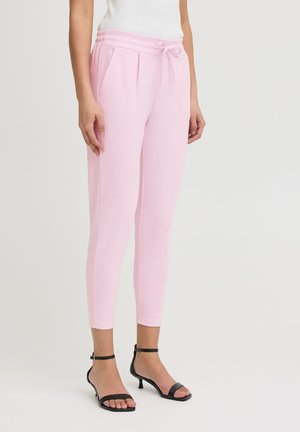 Pantalones jogger ajustados de color rosa claro con cintura elástica y cordón, que cuentan con bolsillos laterales. Tejido suave con una textura blanda.