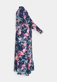 Vestido maxi florido azul marinho com mangas compridas, apresentando padrões de flores rosa e verde. Acento de cintura laçada, tecido fluido e detalhe de fenda lateral.