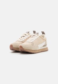 Beige sneakers with mesh upper, suede accents, textured woven sole, and brown rubber outsole. Features lace-up front and pull tab.