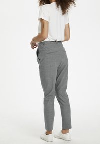 Grå, skräddarsydda byxor med en texturerad tyg, slim fit, bakfickor och midjeband. I kombination med en vit kortärmad skjorta och vita skor.