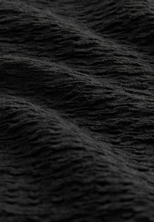 Texturált fekete szövet, hullámos felülettel, puha, szőtt megjelenéssel. Az anyagnak dinamikus, hullámzó mintázata van.