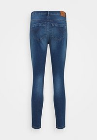 Jeans skinny em denim azul escuro, com uma textura suave, estilo de cinco bolsos e um patch de couro castanho com a marca na parte traseira da cintura.