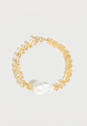 Bracelet avec perles translucides couleur ambre et une seule grande perle blanche irrégulière, fixé par un fermoir en or.