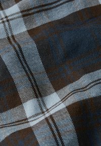 Bruin en blauw geruite stof met scherpe lijnen, een zachte textuur en een geweven patroon met witte accenten.