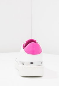 Bílé tenisky s růžovým koženým detailem na patě, metalickým ozdobením a hladkým povrchem. Mají zakulacený tvar a design na snadné obutí.