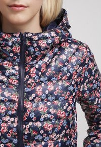 Giacca puffer floreale blu navy con cappuccio, caratterizzata da un design trapuntato e da motivi floreali multicolori. Chiusura con zip sul davanti.