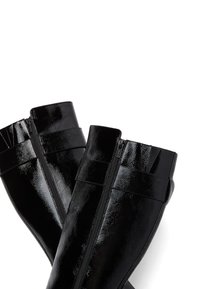 Fekete, térdig érő csizmák fényes felülettel, oldalsó cipzárral és két vízszintes pánttal a tetején a szerkezeti részletekért.