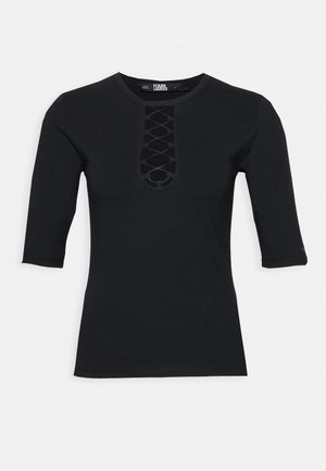Black fitted top with 3/4 sleeves, featuring a crisscross lace-up detail at the front neckline.
