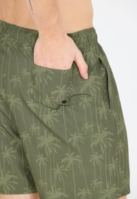 Gröna simshorts med palmträds-mönster, elastiskt midjeband, sidofickor och ett lätt, snabbtorkande material.