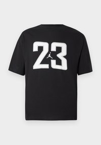 Melnas kokvilnas T-kreklis ar lielu baltu "23" un Jumpman logotipu uz priekšpuses; īsās piedurknes un klasisks apaļais kakla dizains.