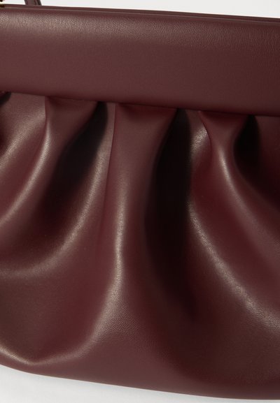Sac à main en cuir bordeaux avec une texture plissée, présentant une finition lisse et un haut structuré. Design compact adapté à un usage quotidien.