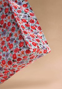 Torebka tote w kwiatowy wzór z wielokolorowym nadrukiem czerwonych, fioletowych i zielonych kwiatów na jasnoniebieskim tle, z przeszytymi brzegami i prostokątnym kształtem.