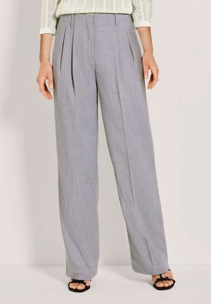 Graue, plissierte Hose mit weitem Schnitt, aus einem strukturierten Stoff; verfügt über eine hohe Taille und Seitentaschen, kombiniert mit schwarzen Sandalen.