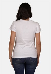 T-shirt bianco a maniche corte con collo a giro, silhouette aderente e tessuto di cotone liscio, mostrato dal retro su uno sfondo neutro.