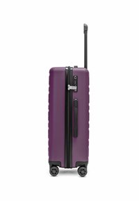 Valigia rigida viola con superficie testurizzata, zip nera, manico retrattile e quattro ruote girevoli. Dotata di lucchetto a combinazione.
