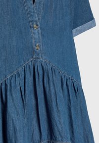 Robe en denim bleu avec manches courtes, deux boutons sur la patte de boutonnage devant et jupe froncée sous la couture de la taille.