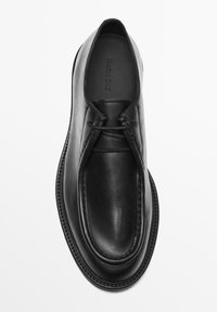 Black leather shoe with a smooth surface, rounded toe, and minimal stitching. Features a slip-on design with no visible hardware.