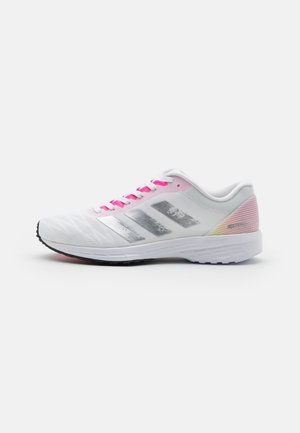 Chaussure de course blanche et rose avec trois bandes argentées sur le côté, lacets roses et semelle amortissante sur fond blanc.