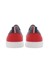 Czerwone zamszowe sneakersy z granatową tkaniną na górze i białymi podeszwami. Tył ma paski w kolorze czerwonym, białym i niebieskim. Okrągły kształt obcasa.