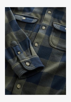 Flanellskjorta i grön och marinblå rutig mönster, med fyra knappar, två bröstfickor och strukturerad tyg. Släta manschetter ingår.