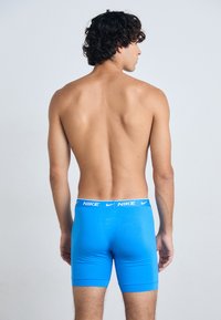 Blue Nike boxer briefs with a white logo waistband, made from a smooth, stretchy material, fitting closely to the body.