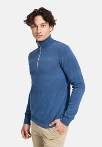 Blauer Strickpullover mit hohem Kragen, der texturierte horizontale Streifen und einen halben Reißverschluss aufweist. Weiches Material und taillierte Passform.