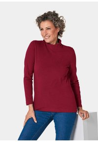 Bordeaux lange mouwen coltrui van zachte stof, met een relaxte pasvorm en gladde textuur, gecombineerd met blauwe jeans.