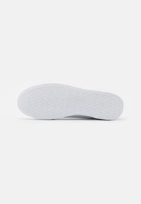 Suola di sneaker bianca con motivo a spina di pesce testurizzato. Finitura liscia, bordi arrotondati, branding minimale in un design sobrio.