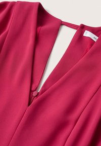 Blouse fuchsia avec un décolleté en V profond et une fermeture éclair. Fabriquée en tissu lisse avec un design épuré et sans motifs visibles.