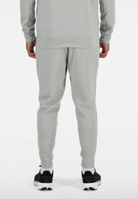 Graue, leichte Jogginghosen mit schmaler Passform, aus weichem Material und im einfarbigen Design, kombiniert mit schwarzen Sportschuhen.