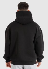 Černá mikina s kapucí, která má uvolněný střih, fleece materiál a žebrované manžety a lem. Pohled zezadu zdůrazňuje oversized design.