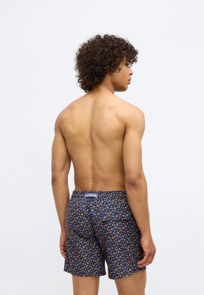 Costume de baie navy cu un model floral colorat, talie elastică și o etichetă de marcă în spate. Material ușor, texturat.