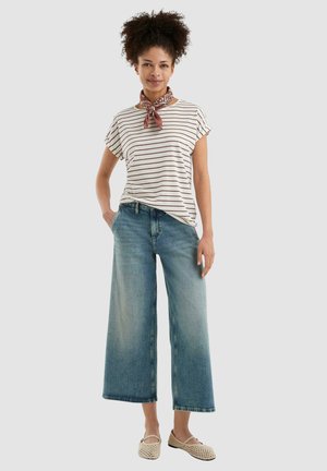 T-shirt a righe a maniche corte in crema e bordeaux, abbinato a jeans in denim scoloriti a gamba larga. Accessoriato con una sciarpa marrone a fantasia e scarpe intrecciate.