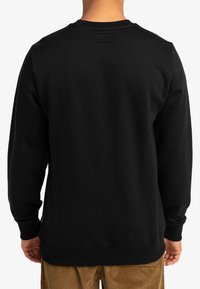 Black cotton sweatshirt with a ribbed crew neck, long sleeves, and a plain design. Features a small brand tag at the bottom hem.