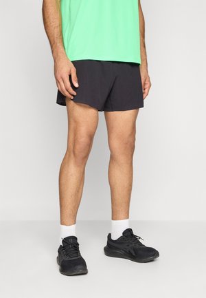 Herrensportshorts aus schwarzem Stoff, kombiniert mit einem hellgrünen Hemd und schwarzen Laufschuhen. Merkmale sind ein schlichtes Design und ein elastischer Bund.