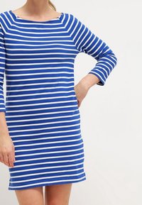 Robe rayée bleu et blanc, en tissu de coton, avec un décolleté bateau et des manches 3/4, présentant une silhouette ajustée.