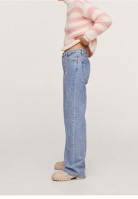 Vaaleansinisiä suoralahkeisia farkkuja, puuvillamateriaalia, käytetyllä viimeistelyllä. Yhdistäytyneet pastelliraidallisen neuleen ja beigejen liukuvaatteiden kanssa.