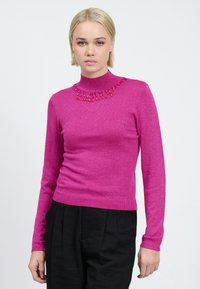 Maglione fucsia a maglia con collo alto e dettagli di collana in perline, caratterizzato da una silhouette aderente e maniche lunghe. Texture morbida e luccicante.