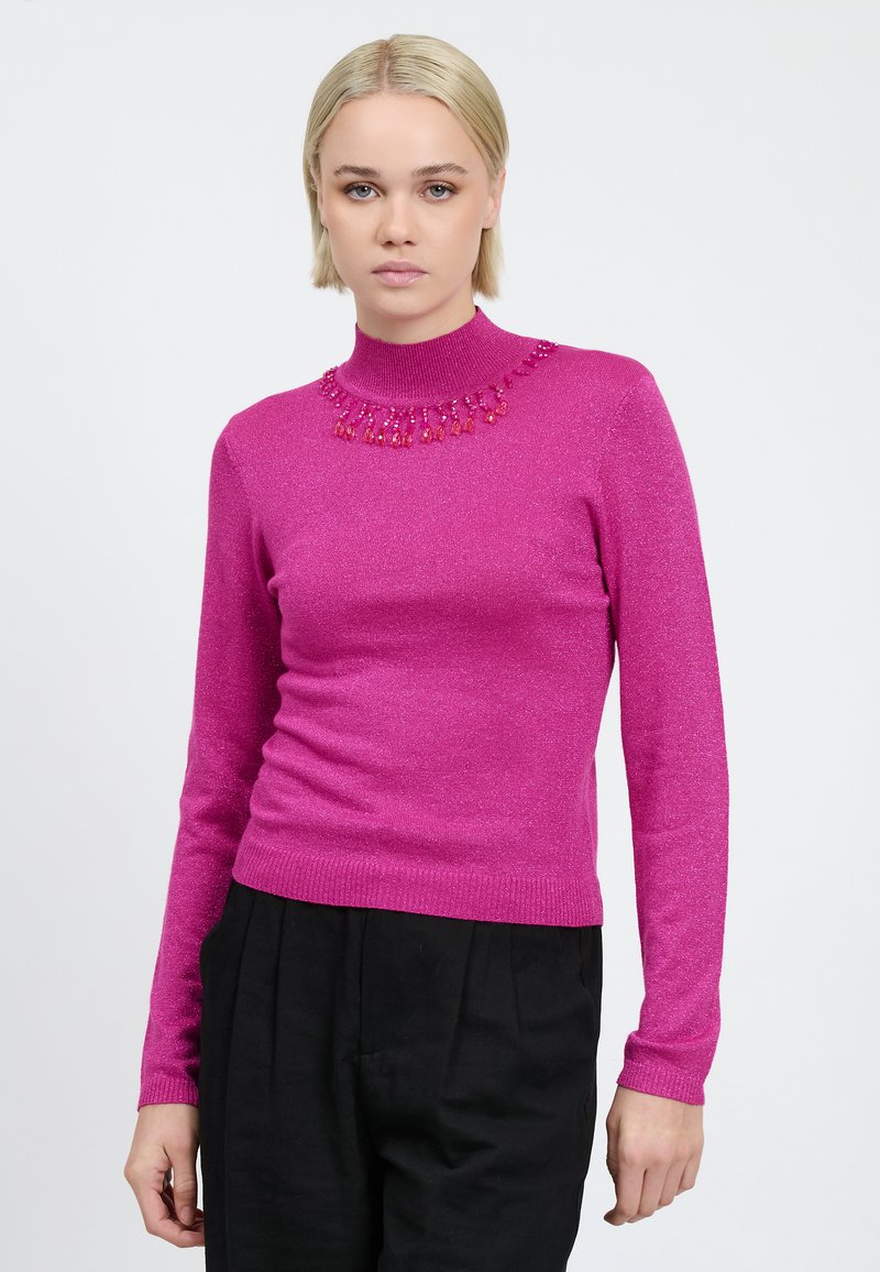 Maglione fucsia a maglia con collo alto e dettagli di collana in perline, caratterizzato da una silhouette aderente e maniche lunghe. Texture morbida e luccicante.