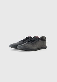 Baskets de sport noires en suède doux et matériaux synthétiques, avec un bout arrondi, un profil bas et une semelle en caoutchouc texturé.