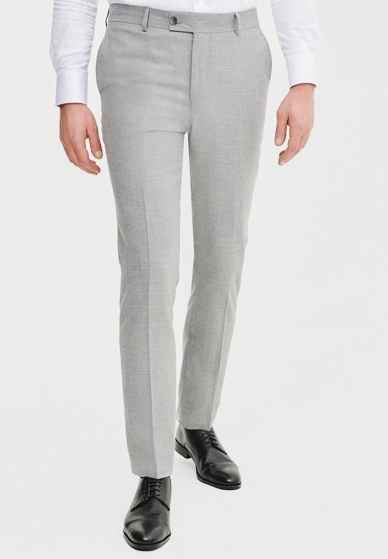 Jasnoszare spodnie z fakturowanej tkaniny, z gładkim przodem i pojedynczym zapięciem na guzik, w połączeniu z czarnymi skórzanymi butami.