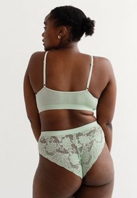 Mintgroene lingerieset met een gladde bh en hoog-hoog panties met kant aan de achterkant, die ingewikkelde bloempatronen en zachte texturen toont.
