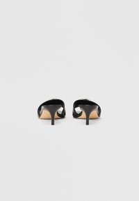 Czarne szpilki z eleganckim, odkrytym tyłem. Wykonane z gładkiej skóry, z ostrym noskiem i wąskim obcasem typu szpilka.