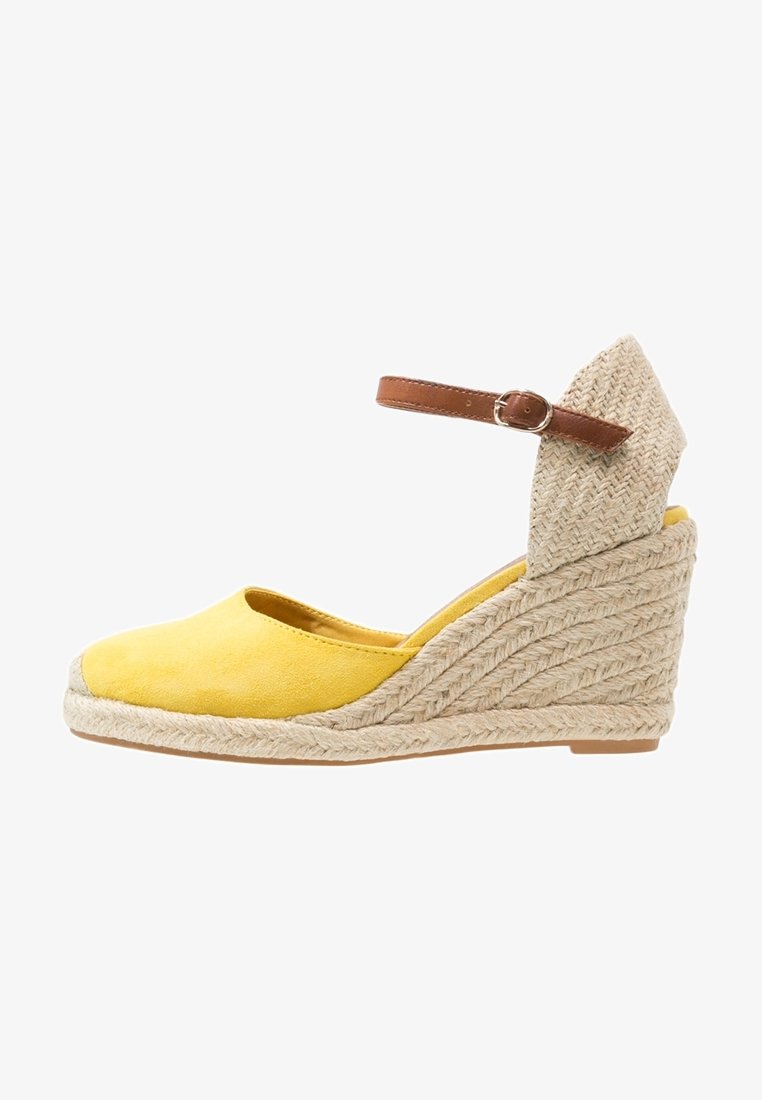 Espadrille compensée jaune avec semelle en jute tressée et bride à la cheville avec boucle marron.
