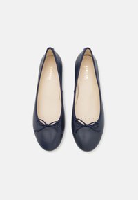 Pantofole ballet in pelle blu navy con punta arrotondata, dettaglio decorativo a fiocco e soletta beige con fori di ventilazione per traspirabilità.