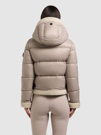 Giacca imbottita beige con cappuccio e polsini in finta pelliccia, caratterizzata da un design trapuntato, orlo elastico e superficie liscia e lucida.